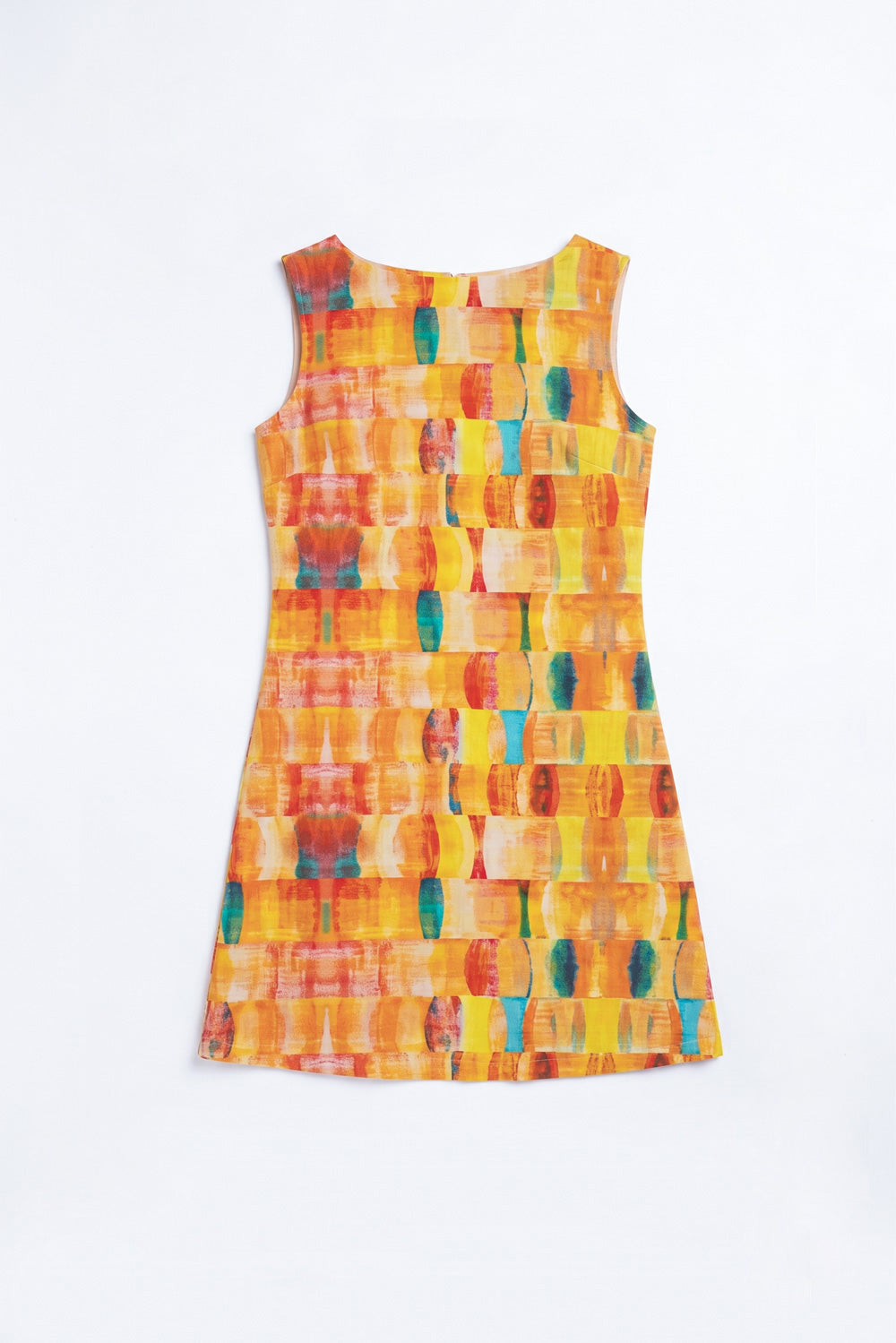 A woman modeling a sleeveless A-line hemp dress with a colorful abstract block pattern in orange, yellow, red, and blue, paired with white sneakers, against a light gray studio background.