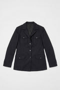 A black utility-style linen jacket with a pointed collar, front button closure, and four flap pockets, laid flat against a light gray background.