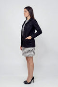 Woman wearing a black linen blazer with patch pockets over a monochrome printed dress, showcasing elegant sustainable women’s fashion.