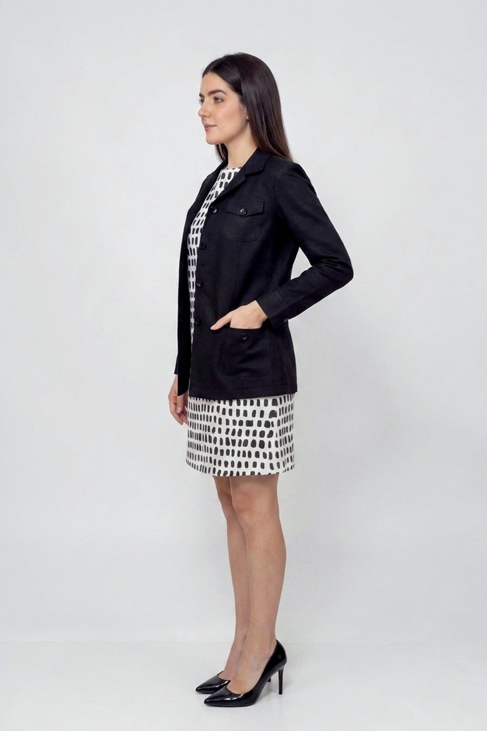 Woman wearing a black linen blazer with patch pockets over a monochrome printed dress, showcasing elegant sustainable women’s fashion.