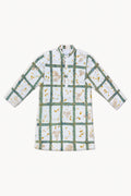 A long-sleeve tunic shirt with a white base, featuring a green grid pattern overlaid with small beige and yellow floral motifs, displayed on a clean white background.