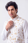 A man wearing a white long-sleeve kurta under a white vest decorated with a gold and brown floral pattern, set against a plain light gray background.