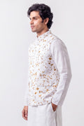 A man wearing a white long-sleeve kurta and a white vest with a brown abstract pattern, photographed against a plain light gray studio background.