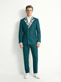 Man wearing a teal suit with a patterned shirt on a white background