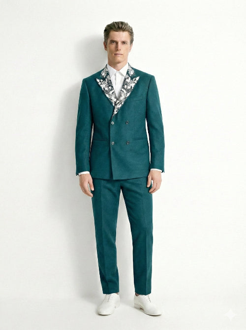 Man wearing a teal suit with a patterned shirt on a white background