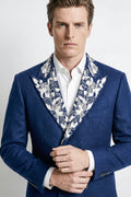 Man wearing a blue suit with a patterned cravat against a white background