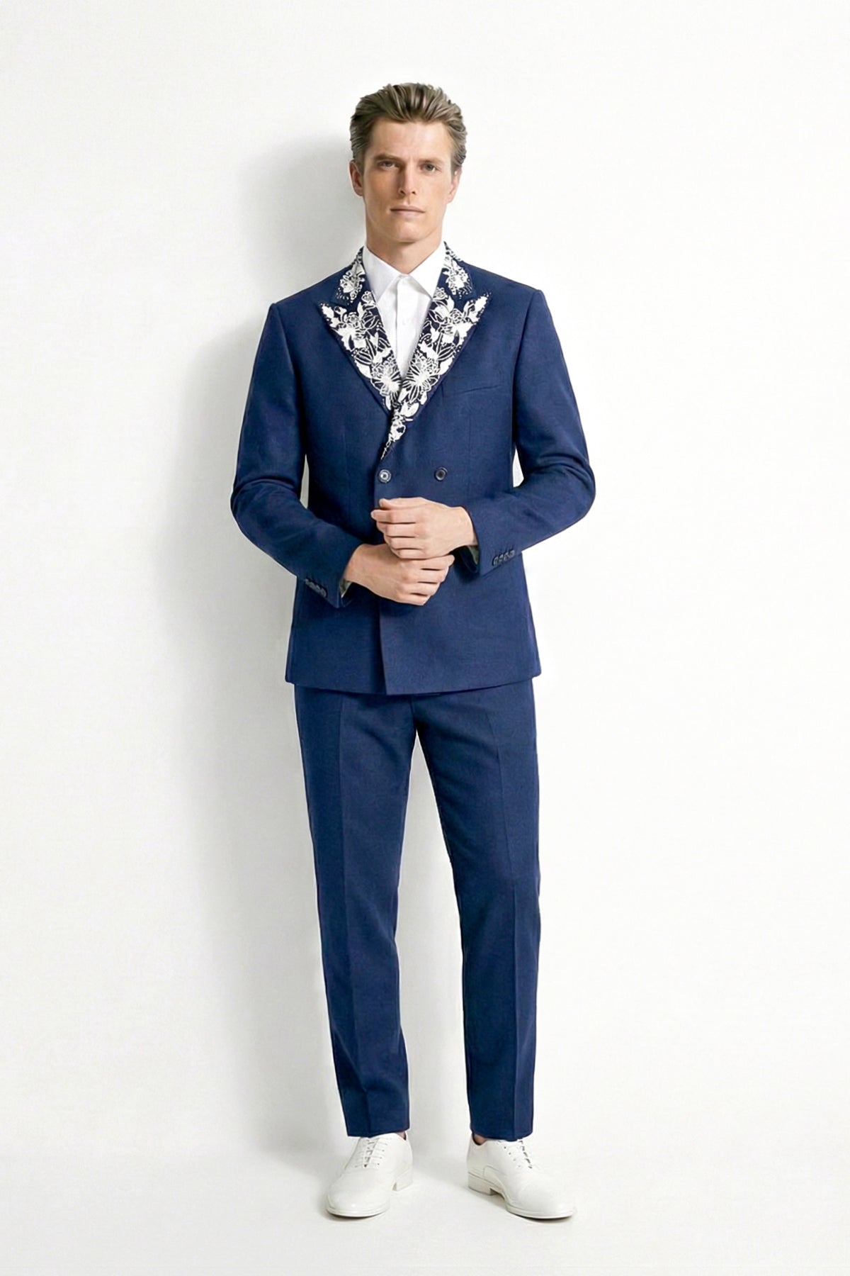 Man wearing a blue suit with a patterned shirt against a white background