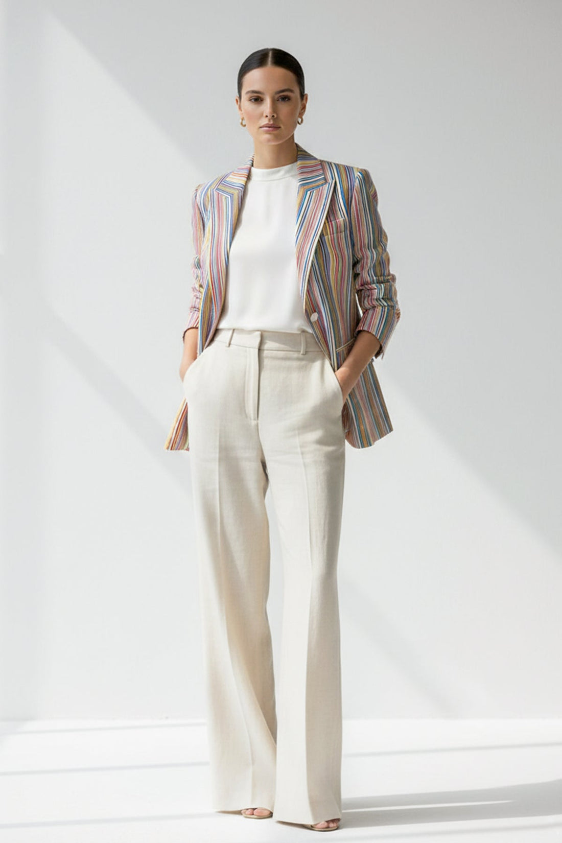 Woman wearing a striped Linen blazer and white pants on a plain background