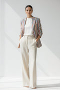 Woman wearing a striped Linen blazer and white pants on a plain background