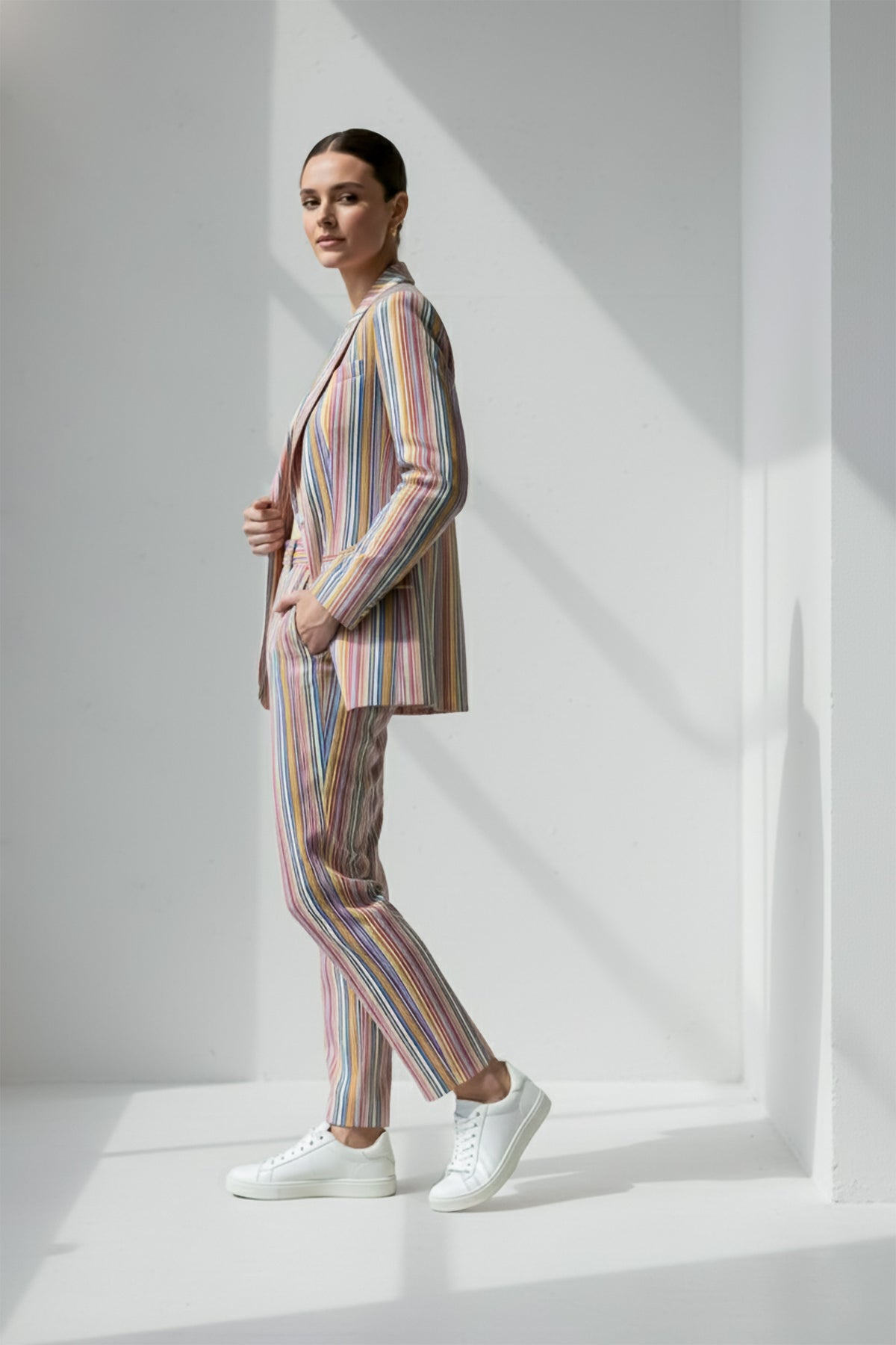 Person wearing a multicolored striped Linen suit standing against a white background