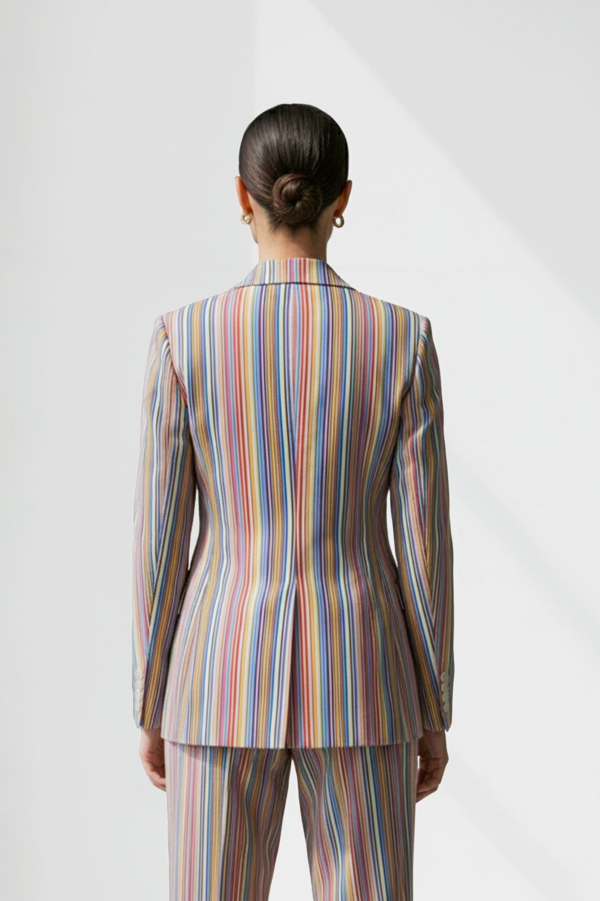 Person wearing a multicolored striped linen suit on a white background