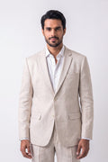 A man wearing a light beige textured linen blazer and matching trousers over a white dress shirt, standing against a plain light gray studio background.