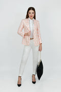 A woman model wearing a peach hemp blazer with a peak lapel, two buttons, and flap pockets, paired with white trousers.