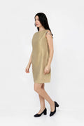 A woman modeling a sleeveless, knee-length metallic champagne-gold silk dress with black heels, standing against a plain white studio background.
