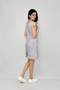 A woman models a mid-length sleeveless linen dress with a geometric pattern, featuring a boat neck and rear zip opening.