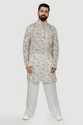 A man wearing a traditional Indian linen kurta with a mandarin collar, featuring a floral print and matching buttons, paired with light-colored trousers.