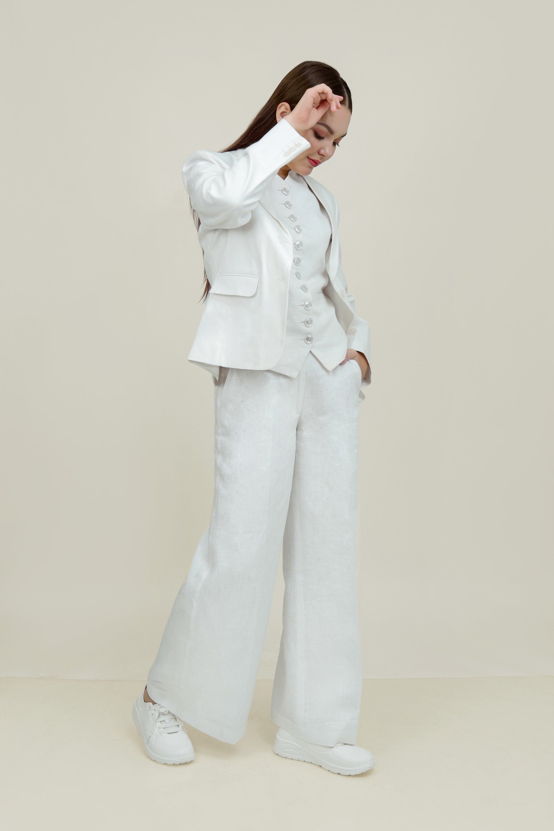 A woman modeling a white linen blazer with a notch lapel, two-button single-breasted design, and flap pockets.