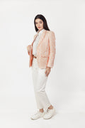 Woman wearing a light pink blazer over a white shirt and pants on a white background