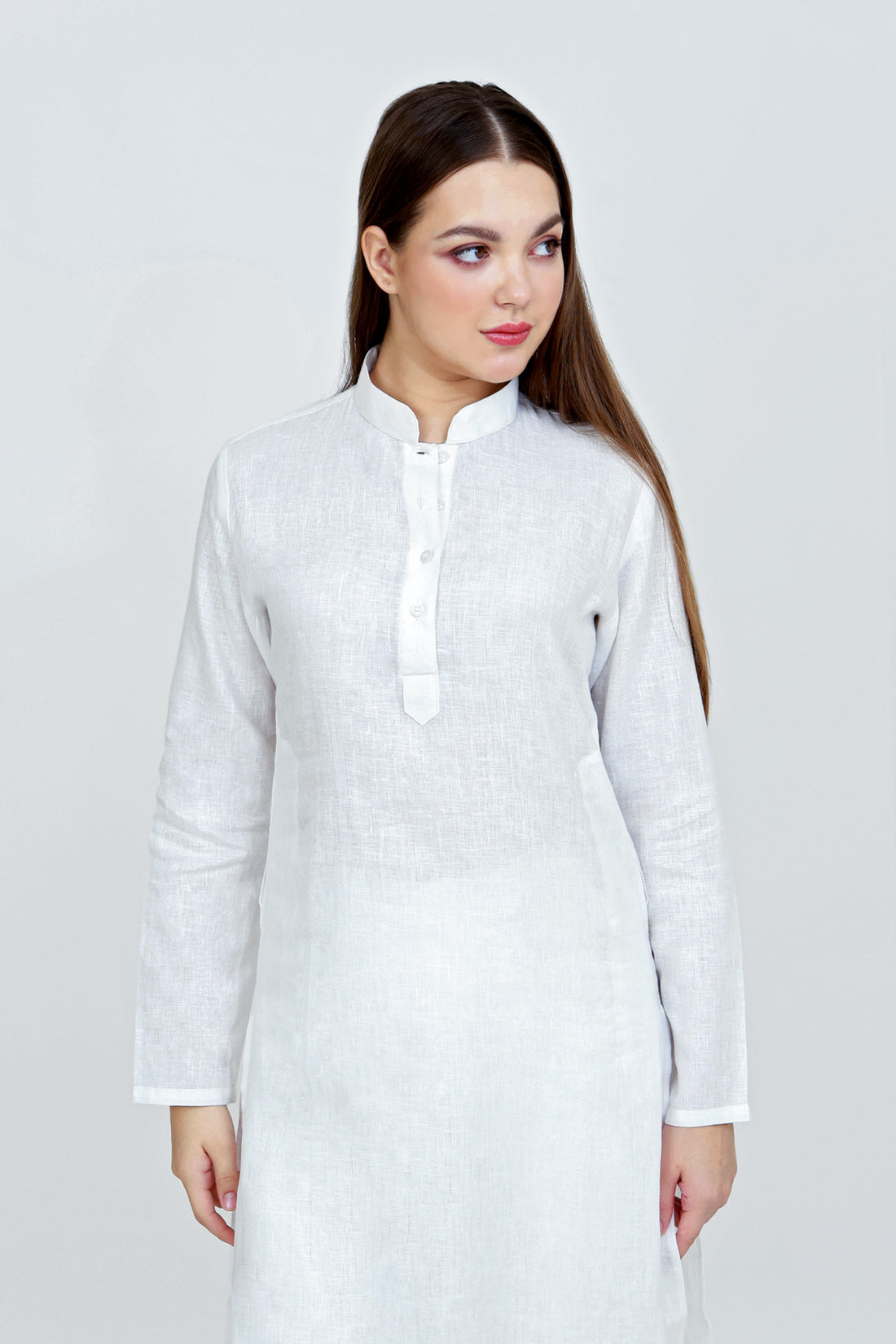 Woman wearing a white long-sleeve shirt against a plain background