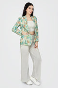 Woman wearing a patterned blazer and light pants on a white background