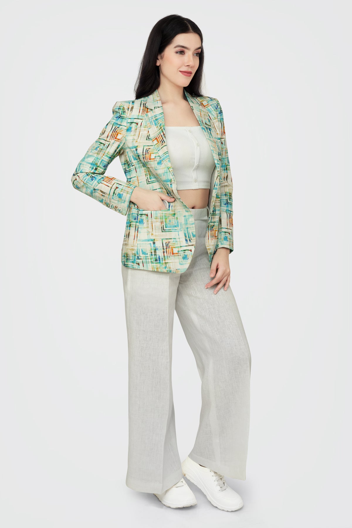 Woman wearing a patterned blazer and light pants on a white background