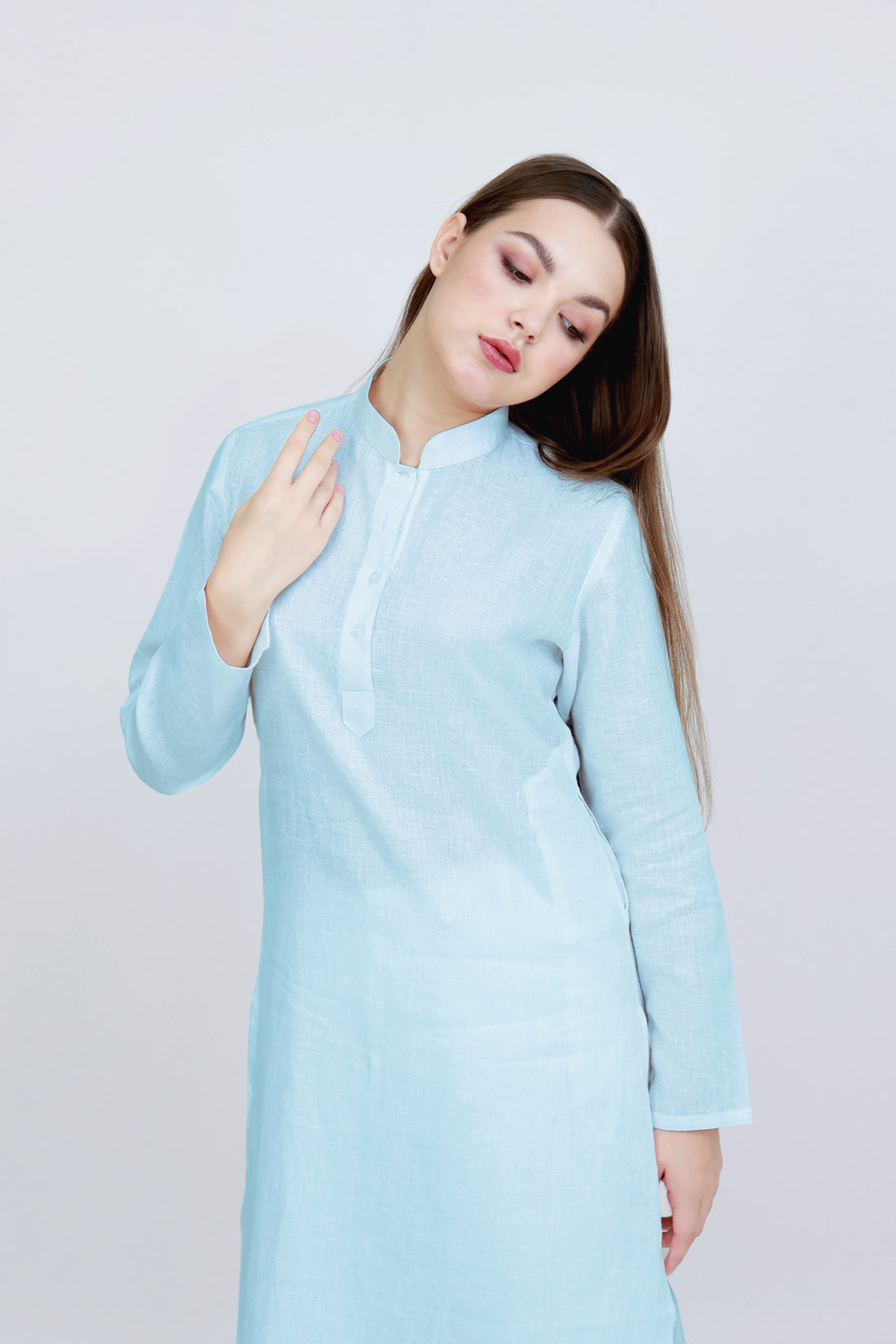 Woman wearing a white long-sleeve shirt against a plain background
