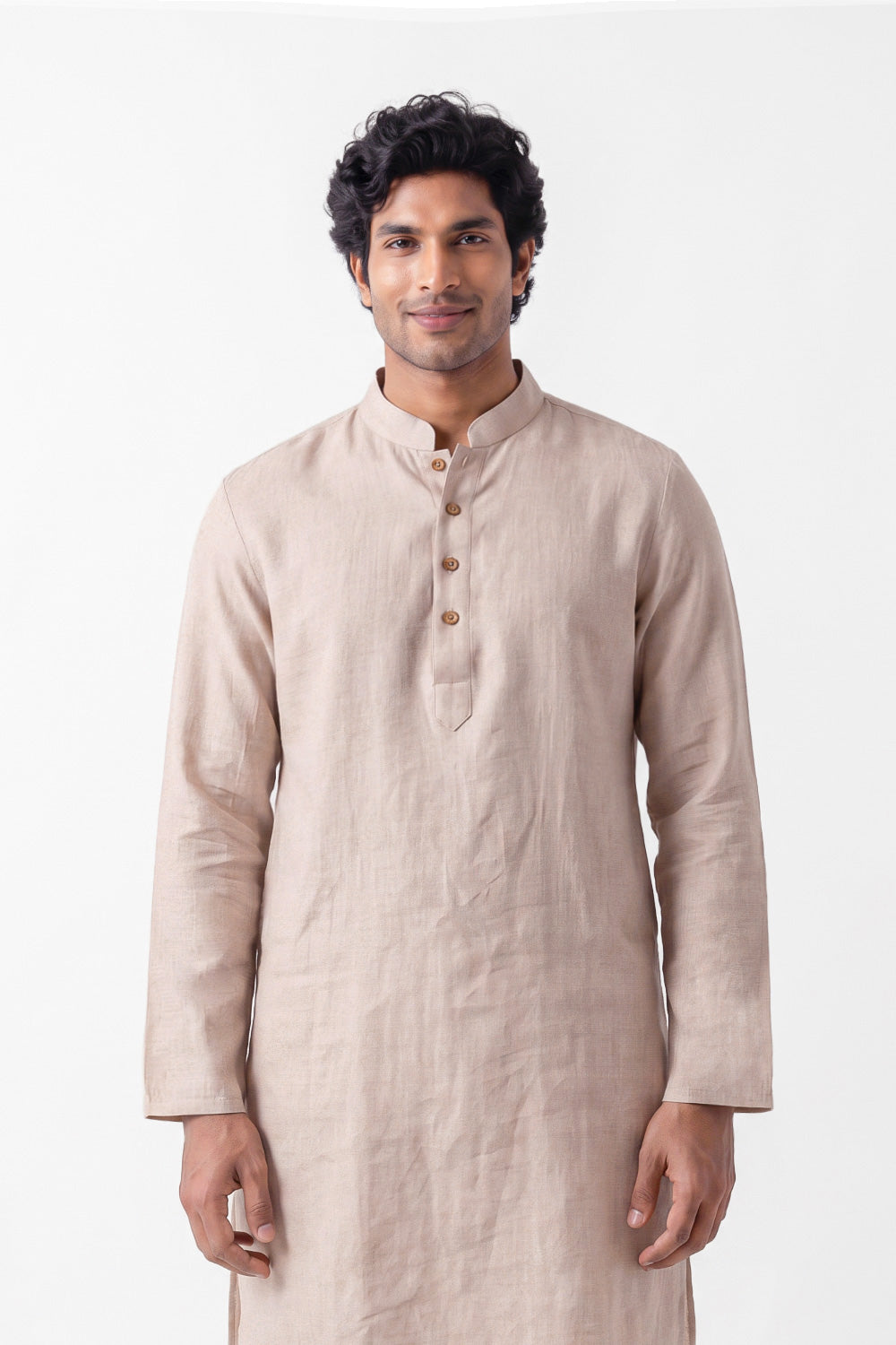 A man wearing a light beige linen long-sleeve kurta with a buttoned mandarin collar, standing against a plain white studio background.
