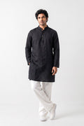 A man modeling a black long-sleeve Linen kurta with a mandarin collar and three-quarter buttons, paired with white trousers and white sneakers, against a plain white studio background.