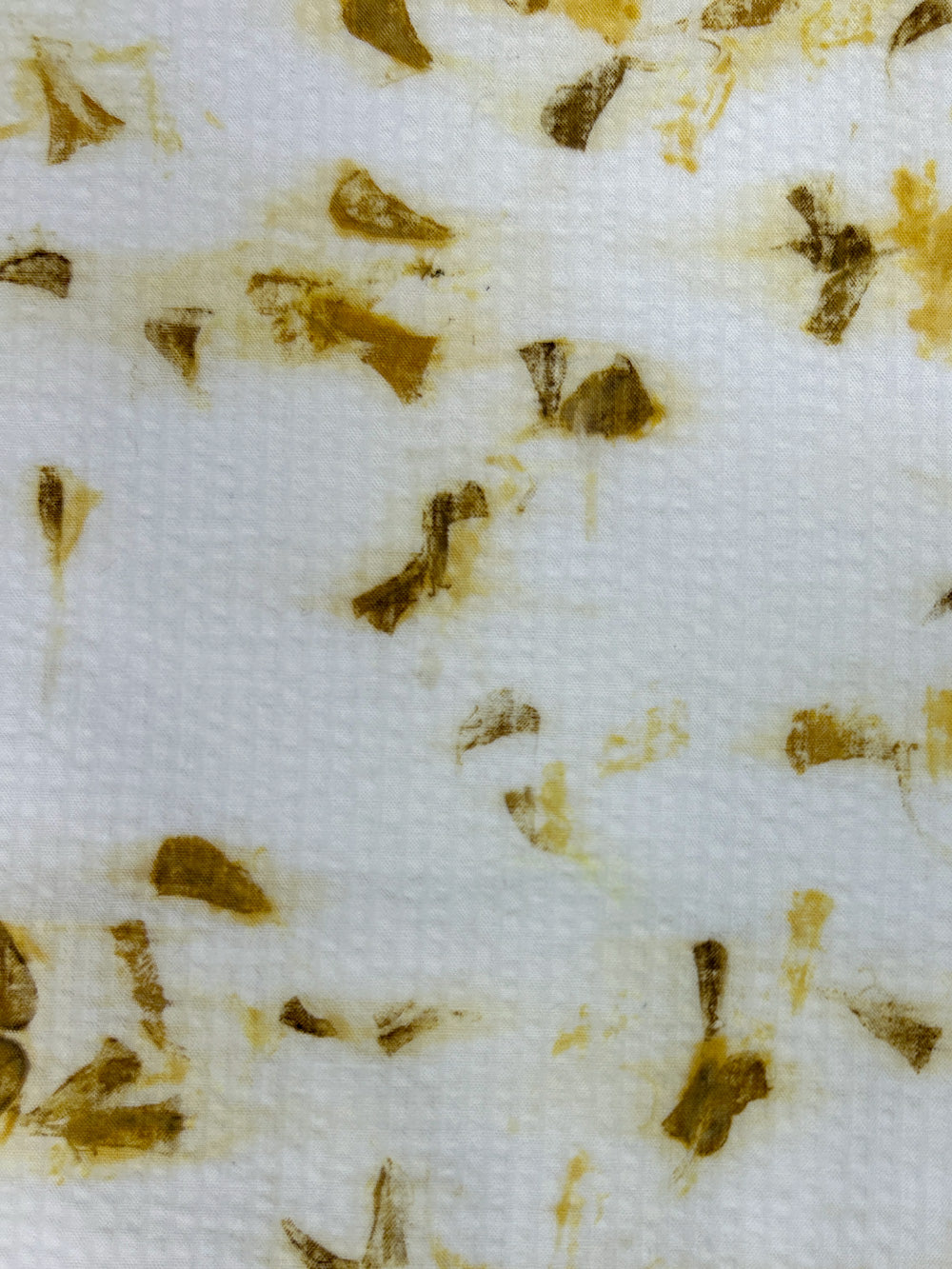 Close-up of marigold petal eco-print on bamboo-cotton seersucker fabric