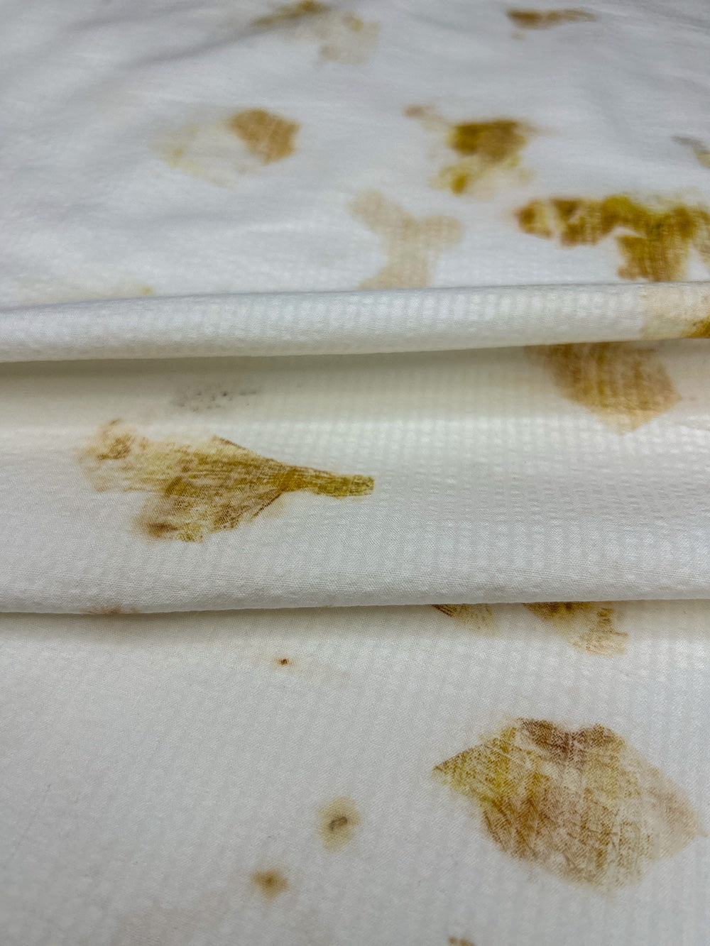 Close-up of bamboo-cotton seersucker fabric folded, hand eco-printed with onion skins