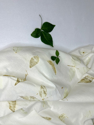 Hemp-cotton fabric hand eco-printed with Bel patra leaves, folded with a fresh Bel leaf sprig on top