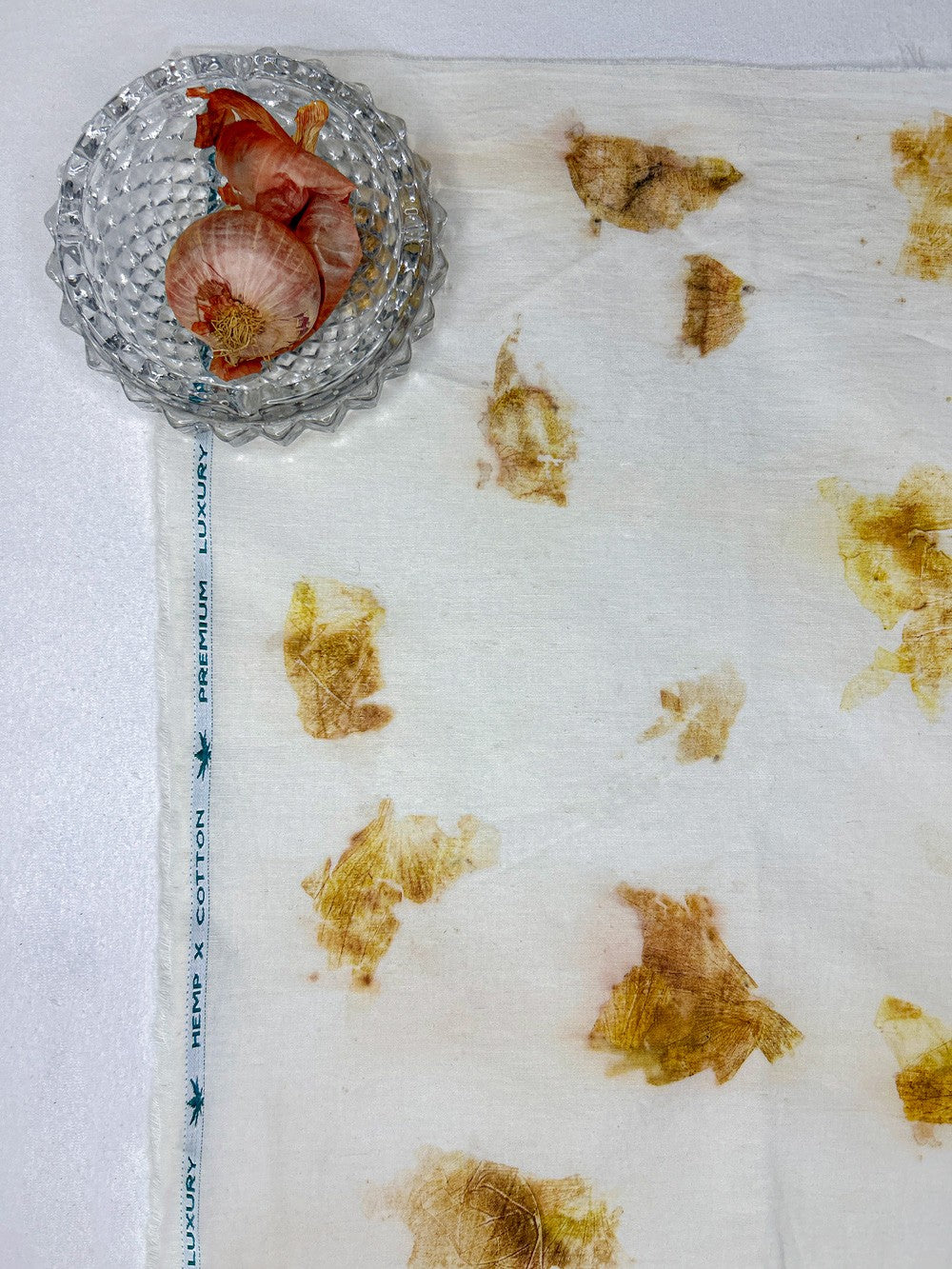 Onions in a glass bowl beside hemp-cotton fabric eco-printed with onion skins