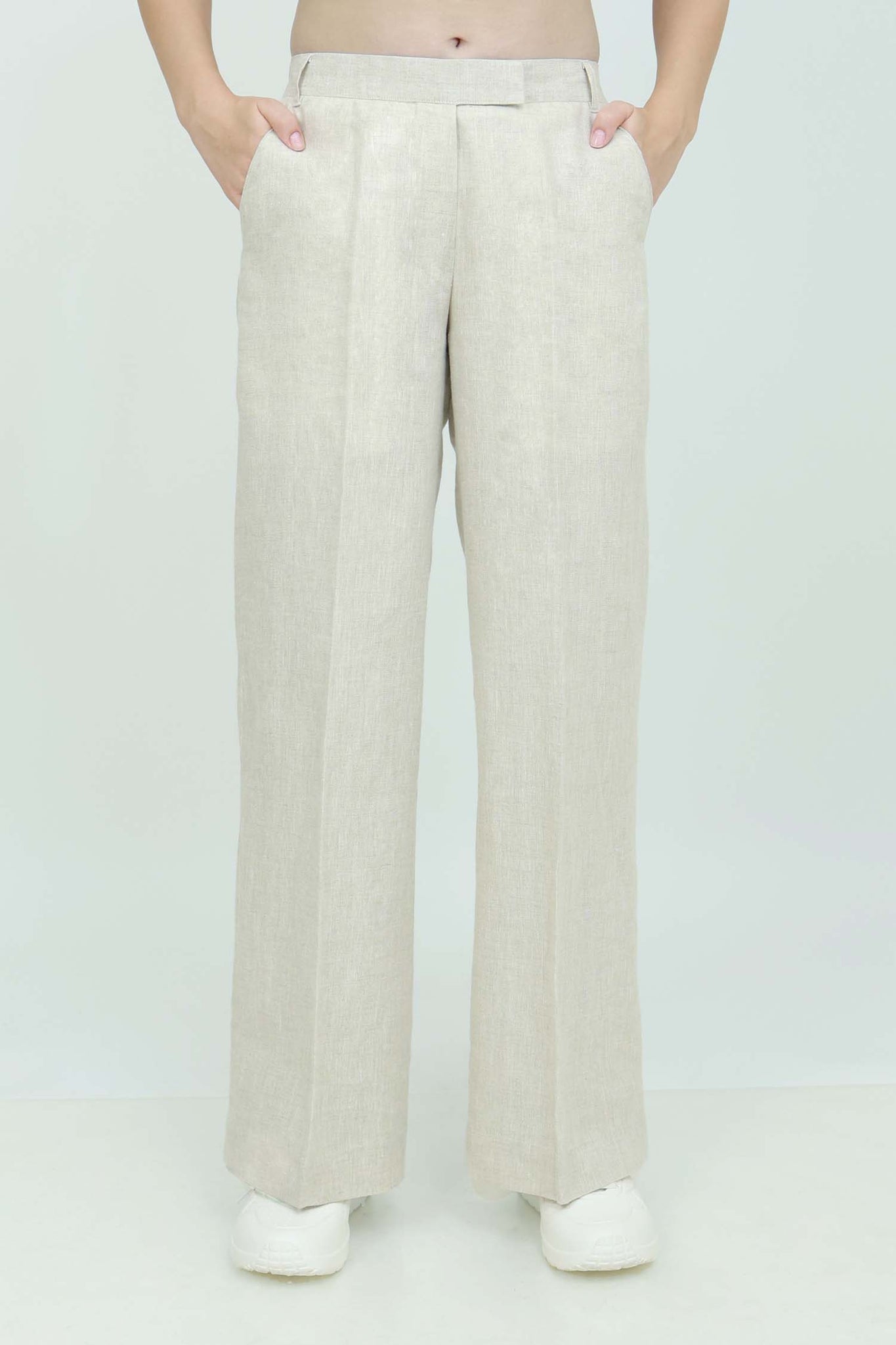 A pair of beige wide-leg trousers with a mid-rise waist, front buttons, and a relaxed fit. The trousers are fully lined and have a hook and bar closure at the waistband with an adjustable elastic belt.