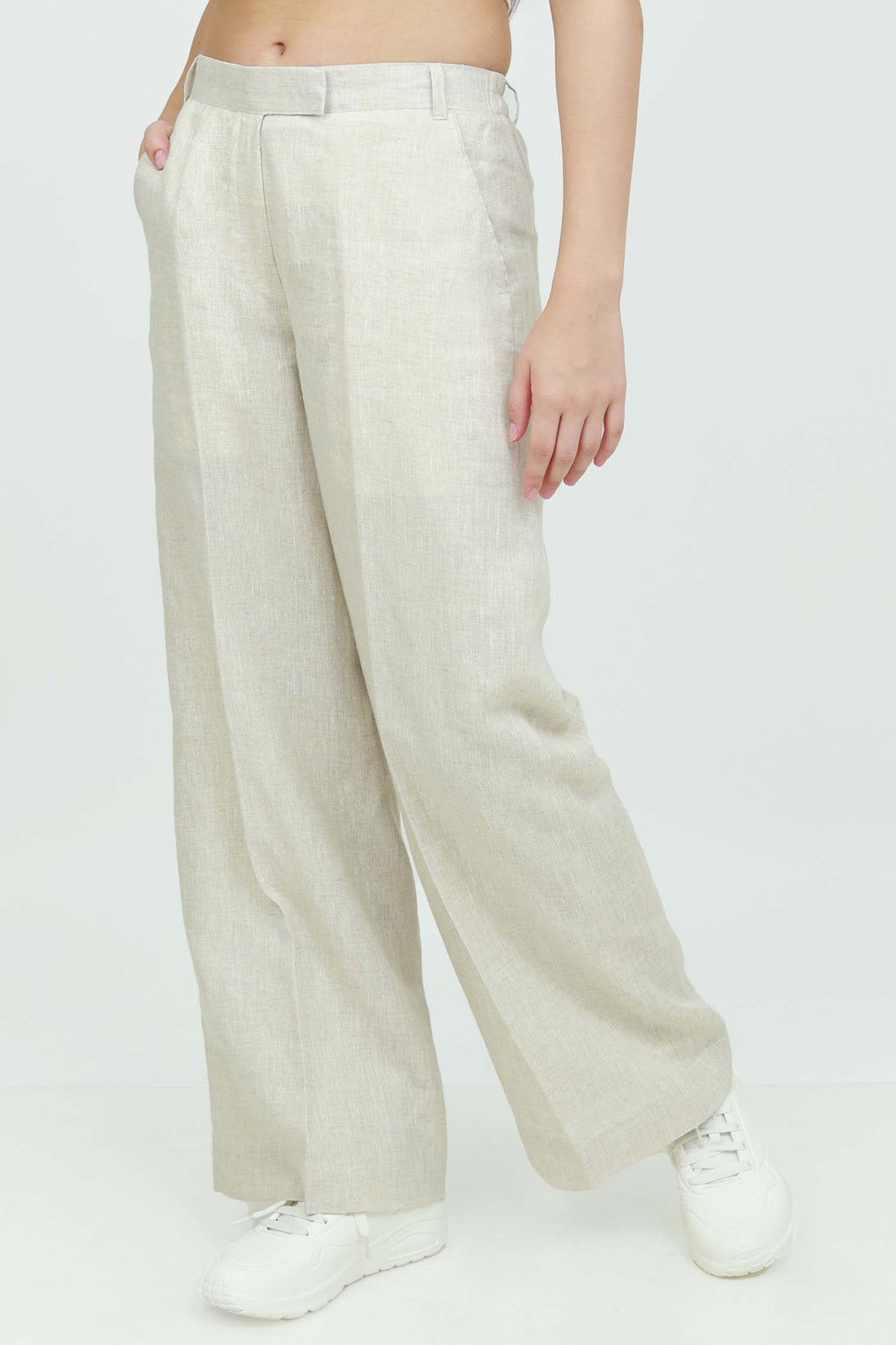 A pair of beige wide-leg trousers with a mid-rise waist, front buttons, and a relaxed fit. The trousers are fully lined and have a hook and bar closure at the waistband with an adjustable elastic belt.