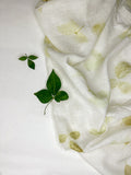 Linen fabric hand eco-printed with leaves, folded with fresh leaf sprigs on top