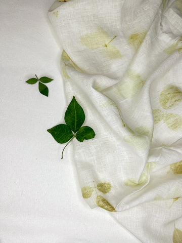 Linen fabric hand eco-printed with leaves, folded with fresh leaf sprigs on top