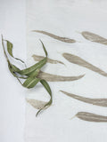 Ivory 40 Lea linen hand eco-printed with eucalyptus leaves, with a dried eucalyptus sprig resting on the cloth