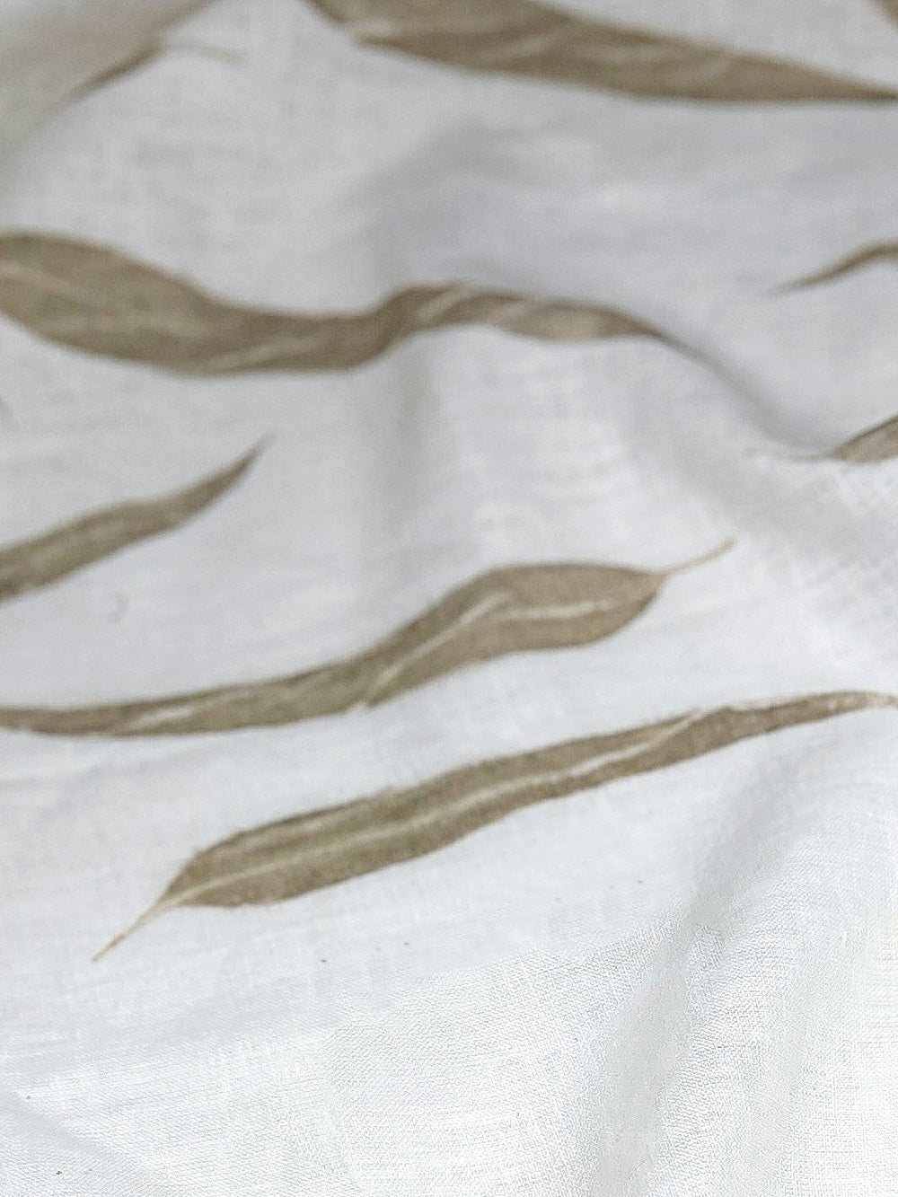 Ivory linen softly draped, showing eucalyptus leaf prints