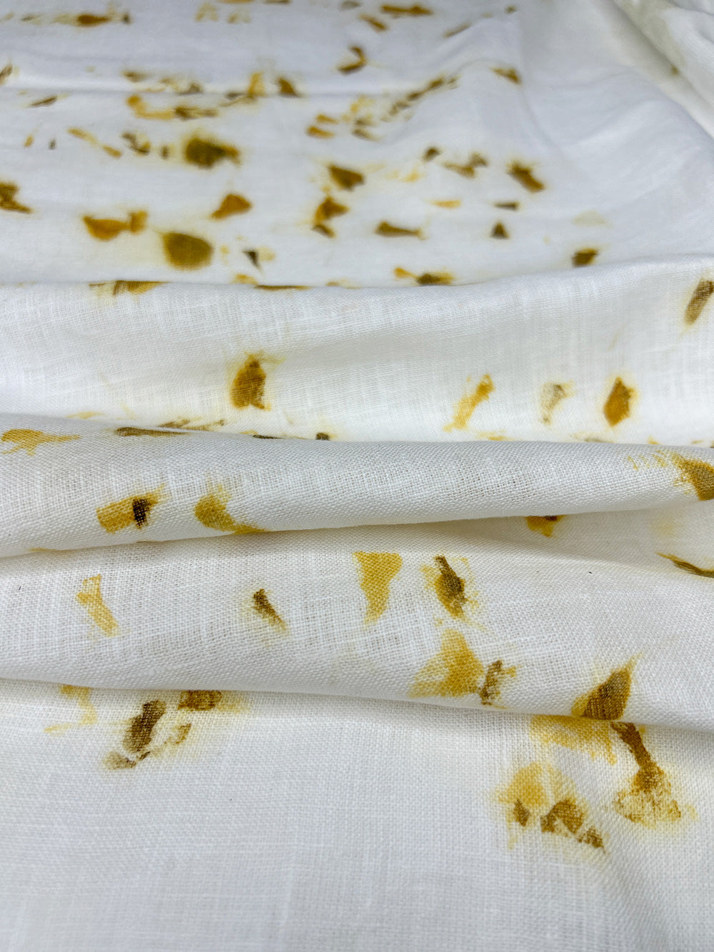 Linen fabric hand eco-printed with marigold petals, draped in soft folds