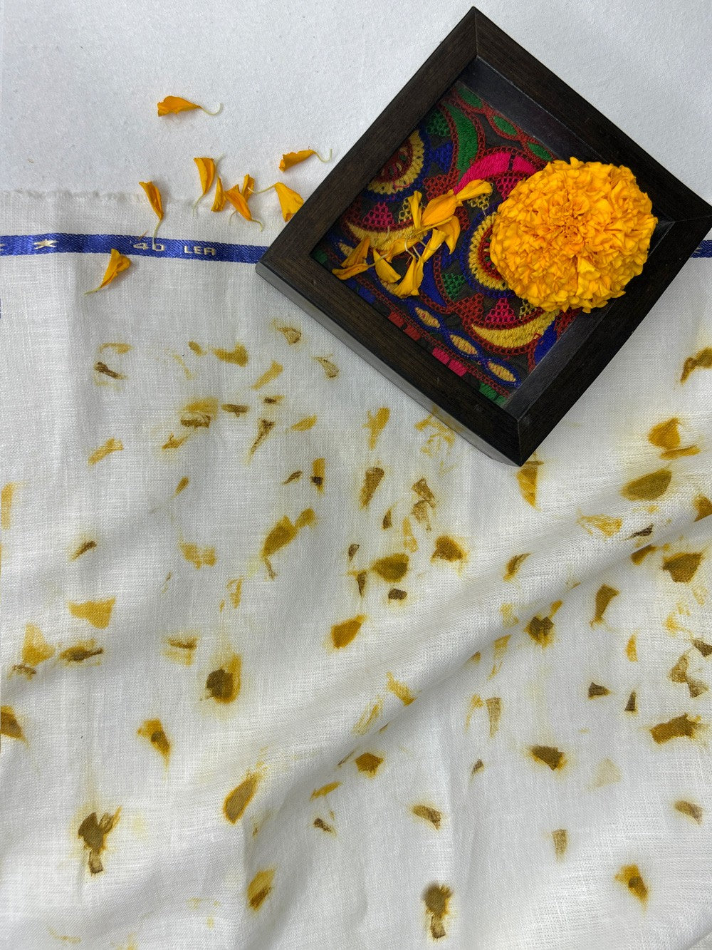 Marigold flower beside linen fabric eco-printed with marigold petals
