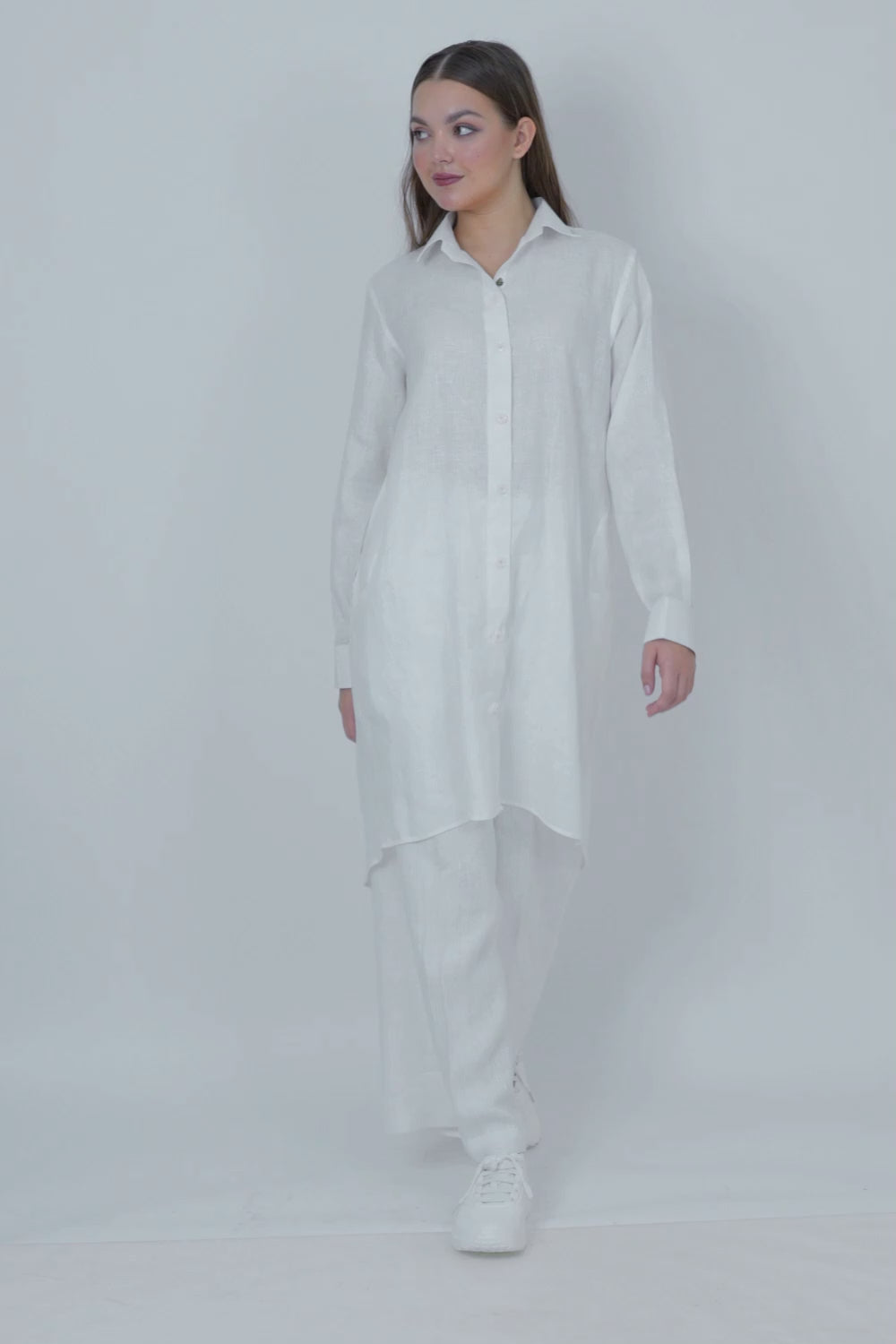 Woman wearing a long white shirt on a white background