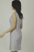 A woman models a mid-length sleeveless linen dress with a geometric pattern, featuring a boat neck and rear zip opening.