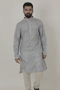 A man wearing a traditional Indian linen kurta with a mandarin collar, featuring a floral print and matching buttons, paired with light-colored trousers.