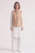 A model wearing a white traditional outfit consisting of a long-sleeve kurta, wide-leg trousers, and white sneakers, layered with a sleeveless  linen  vest featuring a detailed multicolor illustration pattern.