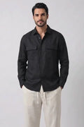 A man modeling a black long-sleeve button-up shirt and off-white hemptrousers against a plain white studio background.