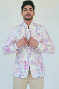 Colorful patterned blazer on worn by man against a white 