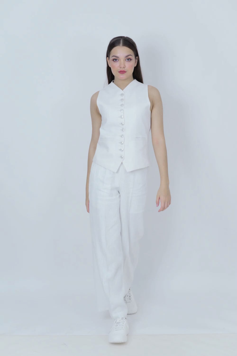 Woman wearing a white sleeveless top and wide-leg pants on a white background