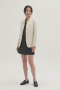 Video of a model wearing the Assam Muga silk jacket in natural gold with a black dress and loafers