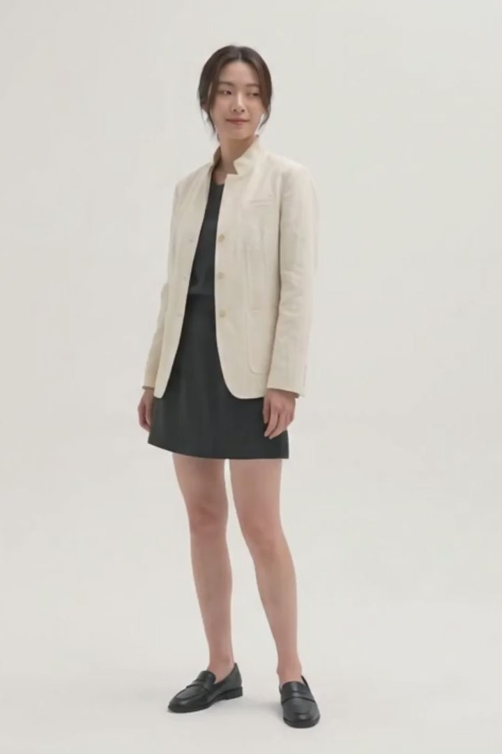 Video of a model wearing the Assam Muga silk jacket in natural gold with a black dress and loafers