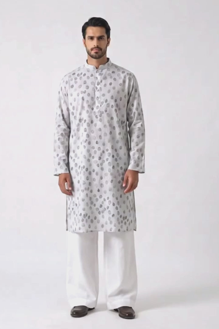 A man modeling a light gray long-sleeve hemp kurta with a silver-gray circular pattern, paired with white trousers and dark brown shoes, standing against a plain white studio background.